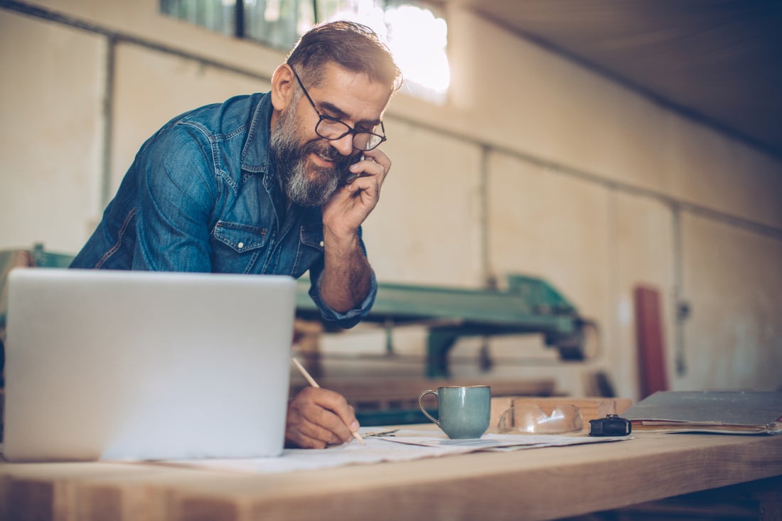 a man sitting at a table looking at a laptop